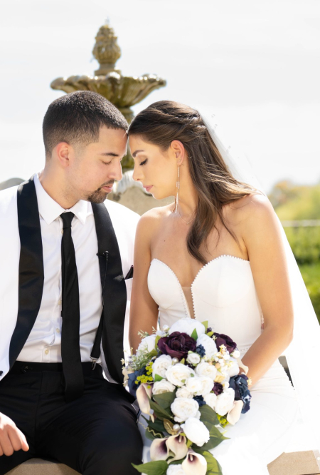 Bride and groom sitting close together, touching foreheads and holding a bouquet, a romantic moment captured by affordable wedding photographers in Columbus, Ohio.