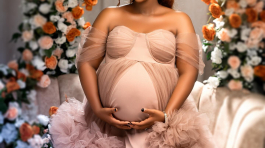 Radiant pregnant woman in a flowing pink gown, surrounded by flowers, captured by black photographers in Columbus, Ohio, specializing in family and maternity photography in Ohio.