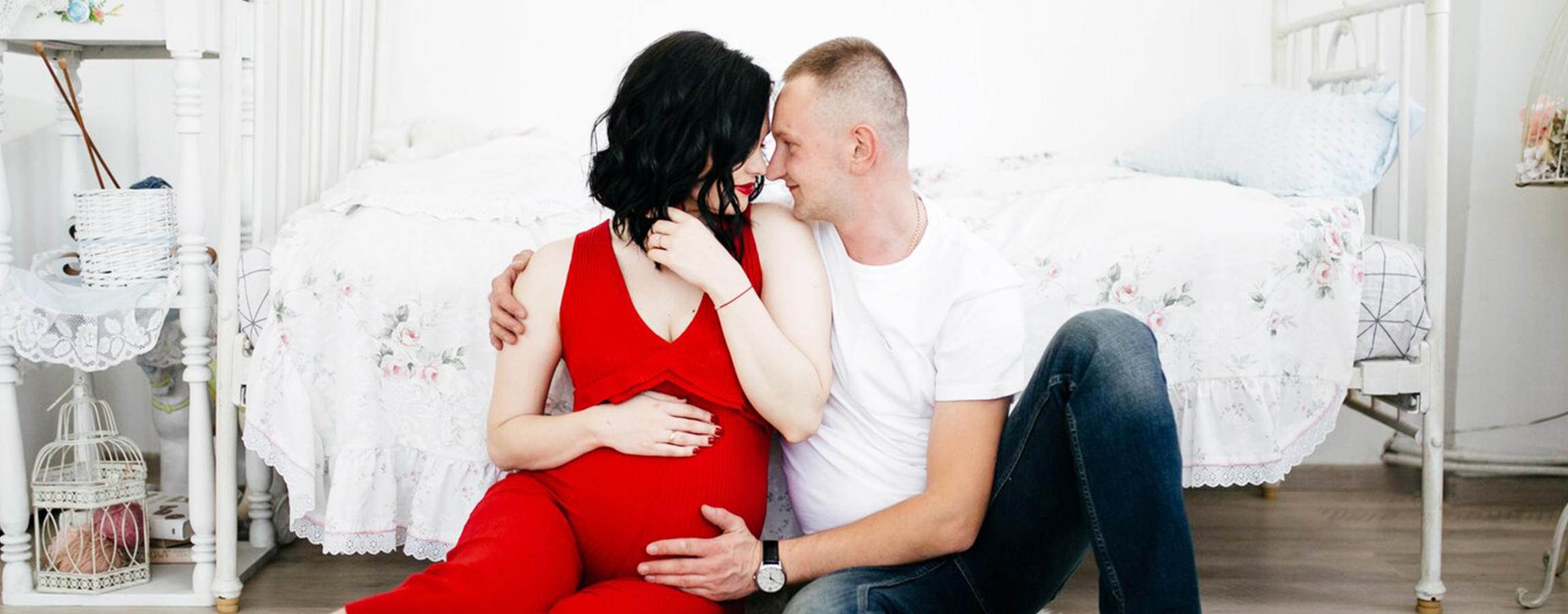 Expecting couple sitting on floor in cozy room woman wearing red dress while man in white shirt embraces her lovingly family joy and anticipation of new life together