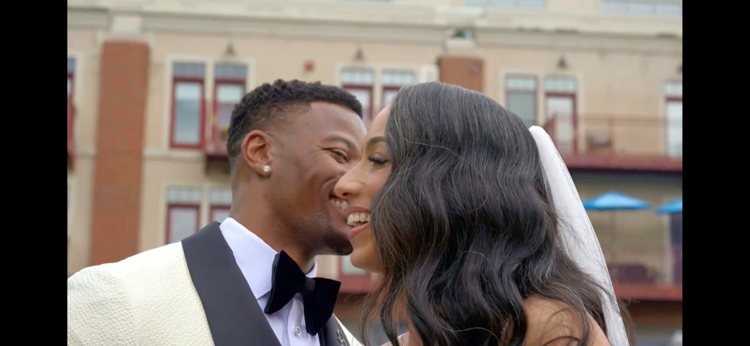 Bride and groom sharing a joyful moment on their wedding day in an urban setting with elegant backgrounds and natural light highlighting their happiness and connection.