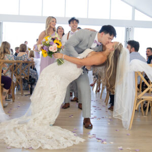 Bride and groom share a romantic dance kiss during their wedding ceremony surrounded by guests in a beautifully decorated venue filled with joy and celebration.
