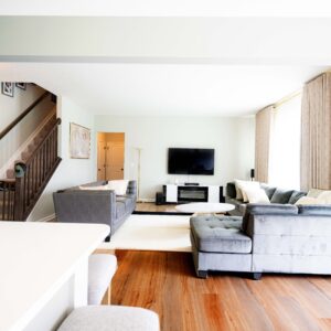 Modern living room with gray sectional sofa natural light from large windows and wooden flooring featuring a flat screen TV and elegant decor for a cozy ambiance