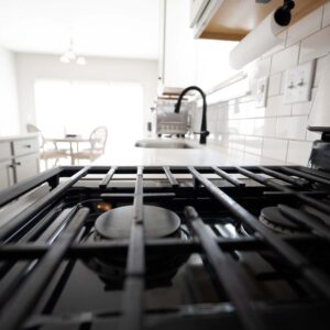 Modern kitchen featuring a close-up of a sleek stovetop with a minimalist design open dining area with natural light in the background ideal for cooking and entertaining