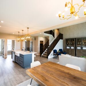 Spacious modern open-concept kitchen and dining area featuring elegant lighting, wooden flooring, and stylish cabinetry, enhancing a warm and inviting atmosphere for living.