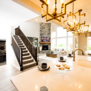 Modern open-concept living room with sleek kitchen island and elegant wooden staircase leading to upper floor featuring stylish lighting and cozy fireplace ambiance.