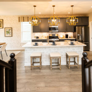 Modern kitchen with a stylish island and stools wood flooring elegant lighting fixtures gray cabinetry stainless steel appliances and natural light from windows