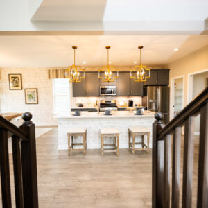 Modern kitchen interior with sleek design featuring a large island bar with stools elegant pendant lighting stainless steel appliances and wood flooring.