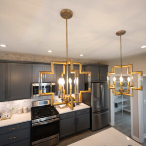 Modern kitchen with stylish gray cabinets, stainless steel appliances, and elegant gold geometric pendant lighting. Bright and inviting cooking space with a contemporary design.