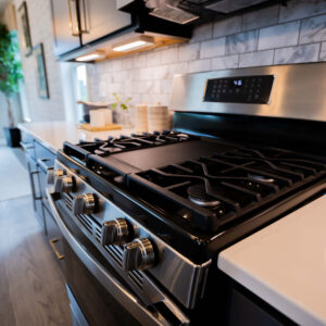 Modern stainless steel gas stove with black grates in a stylish kitchen featuring white countertops and subway tile backsplash bright ambiance with outdoor view