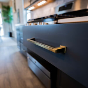Modern kitchen interior featuring sleek blue cabinets with stylish gold handles natural light filtering through large windows creating a warm and inviting atmosphere
