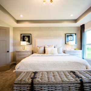 Modern bedroom design featuring a cozy queen-sized bed with white bedding soft lighting and chic decor. Large windows offer natural light for a welcoming atmosphere.
