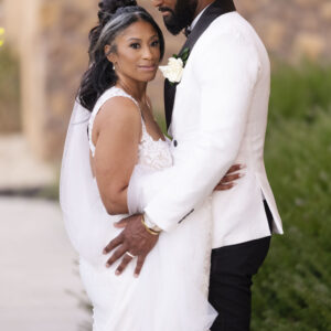 Elegant bride and groom embracing outdoors in stylish wedding attire, highlighting their love and the beauty of their special day amidst a serene natural setting.