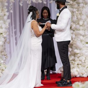 Bride and groom exchange vows in a beautiful wedding ceremony with elegant floral decorations and a red carpet creating a romantic atmosphere.
