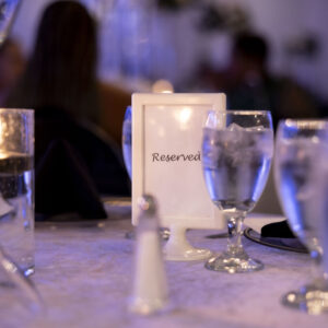 Elegant restaurant table setting with a reserved sign surrounded by glasses and candles creating a warm and inviting ambiance for a special occasion or event.