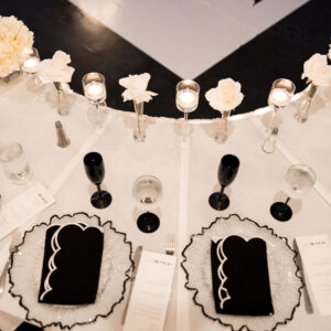 Elegant black and white table setting with floral centerpieces and candlelight creating a sophisticated ambiance for a formal dining experience.
