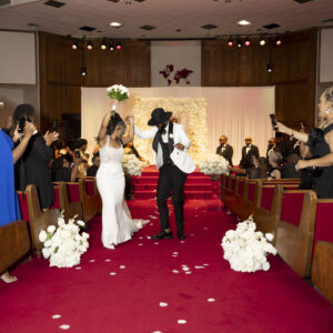 Bride and groom celebrate joyfully as they walk down the aisle in a beautifully decorated church wedding ceremony surrounded by applauding guests capturing the moment.