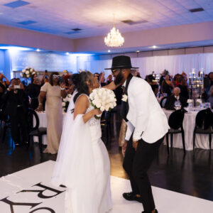 Bride and groom joyfully dancing at wedding reception in elegant venue surrounded by guests white and black decor white floral bouquet festive atmosphere romantic evening