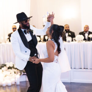 A joyful couple elegantly dances at their wedding reception in a beautifully decorated venue with flowers and candles creating a romantic atmosphere.