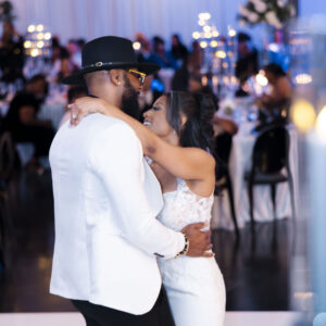 A couple shares a romantic dance at their wedding reception in an elegantly decorated venue, creating a memorable and joyful moment surrounded by guests and candlelight.
