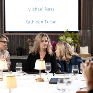 Corporate team attending a business presentation in a modern meeting room with a presenter speaking beside a screen