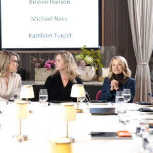 Corporate team attending a business presentation in a modern meeting room with a presenter speaking beside a screen
