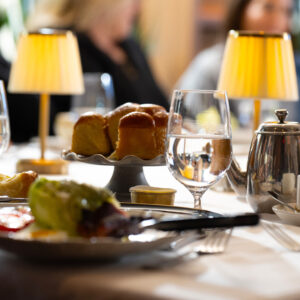 Elegant dining table set for a meal features glasses of water salad and dinner rolls with soft lighting from table lamps creating a cozy and inviting atmosphere