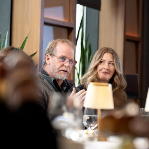 Corporate event photo showing attendees engaged in conversation over a formal meal.