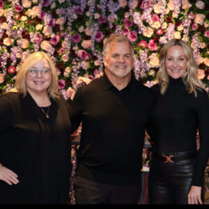 Team members smiling together during a business event with a vibrant floral background
