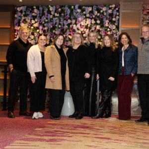 Corporate event group photo with participants standing before a decorative flower