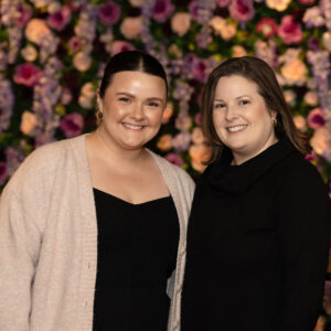 Corporate event portrait of two people standing before a vibrant flower wall