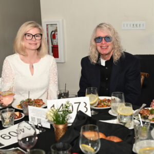 Two people enjoying a meal at a formal event seated at a table with plates of food and drinks visible creating a lively and festive atmosphere.