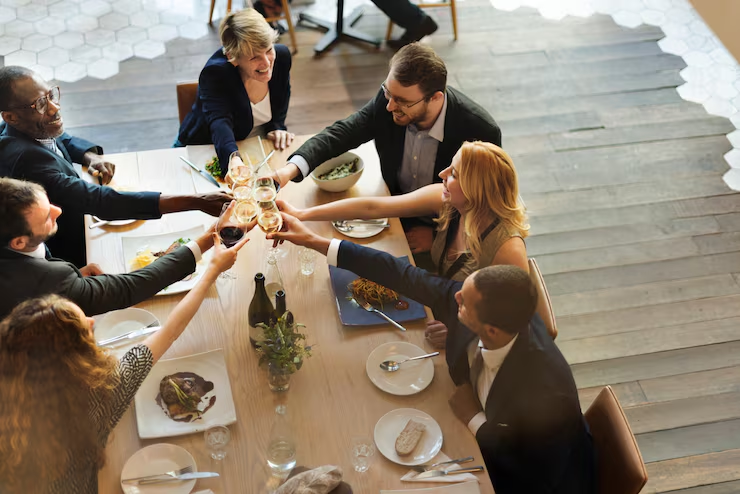Business professionals gathered around a table raising glasses for a toast at a formal meeting or event in a sophisticated dining setting with elegant place settings.