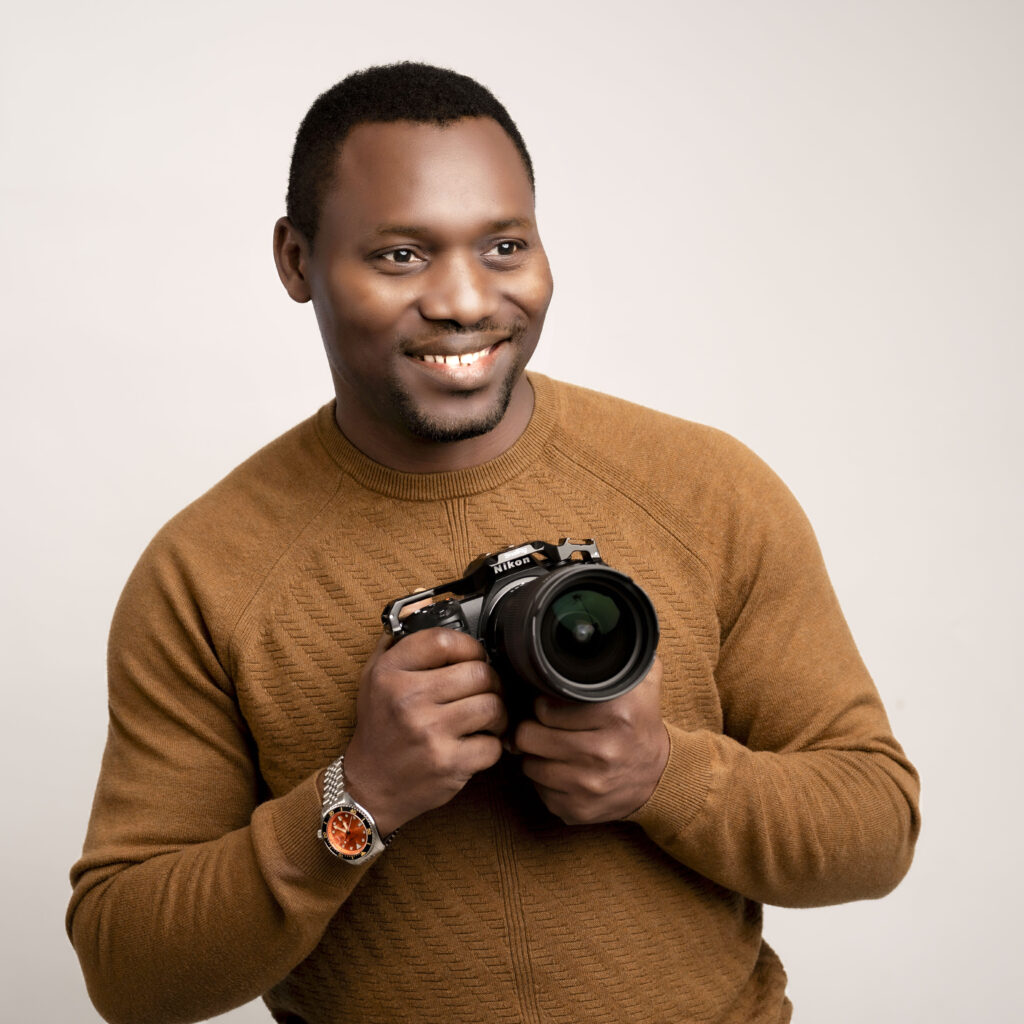 Ola, owner of BigChamps Photography, smiling while holding a Nikon mirrorless camera during a professional portrait in Ohio.